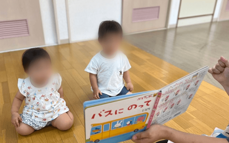 1歳児に絵本を読み聞かせしている画像